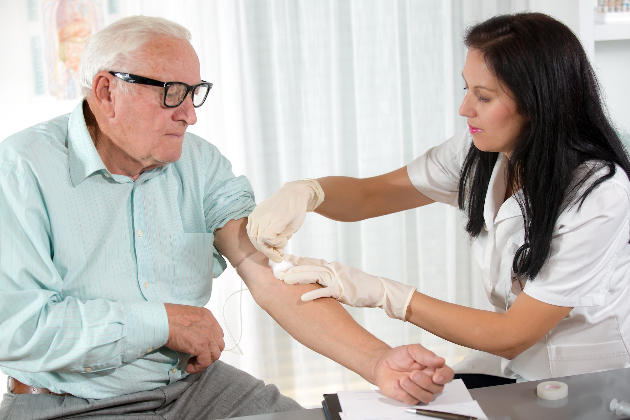 Nurse draws blood from arm of senior man for Alzheimer's test.